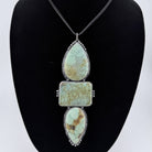 Necklace with turquoise stone pendants on a black bust against a white background