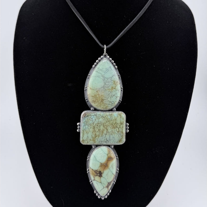 Necklace with turquoise stone pendants on a black bust against a white background
